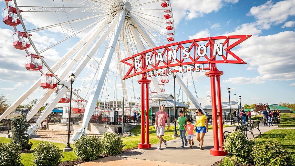 Ground view of the Branson Ferris Wheel and a family walking out of the attraction under the sign in Branson, Missouri, USA