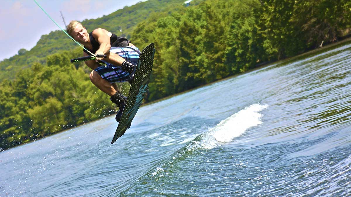 man water skiing on Table Rock Lake with green trees in background in Branson, Missouri, USA