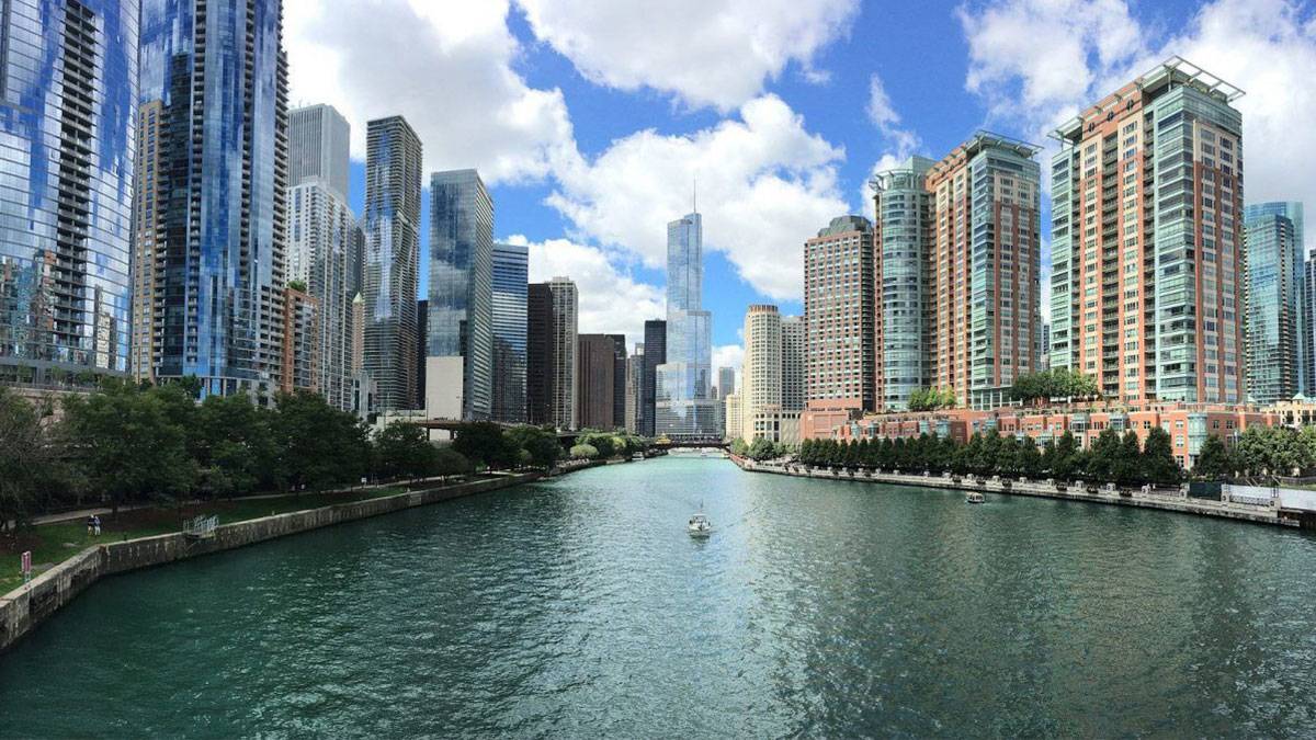 view of the buildings and architecture along the chicago river during the daytime with blue skies and clouds