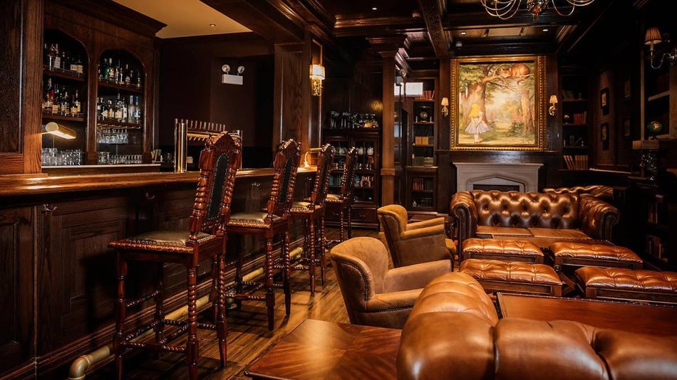 Seating area with large leather couches and chairs on the right and a bar on the left with a fireplace in the back at The Darling in Chicago, Illinois, USA