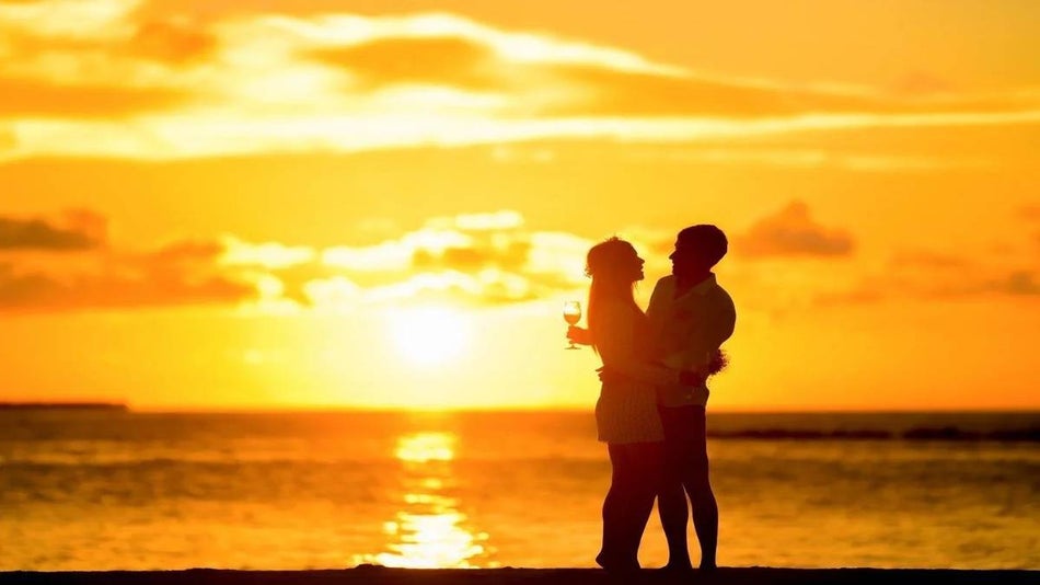romantic couple on the beach at sunset with wine