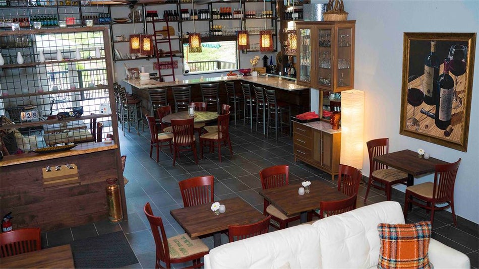 A dining room with dark wooden tables with a little flower on them and red chairs with a bar in the back at Red Oak Bistro in Gatlinburg, Tennessee, USA
