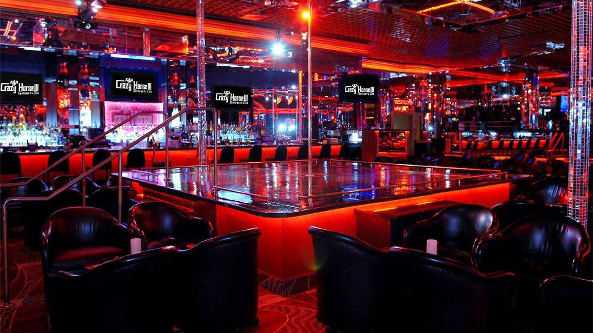 View of an empty stage with a pole in the middle surrounded by black leather chairs and a bar in the back ground at Crazy Horse 3 in Las Vegas, Nevada, USA