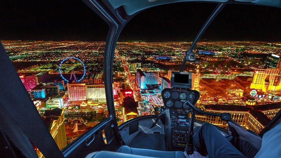 View of the interior front seats of a helicopter with a view of the night lights glowing through the window in Las Vegas, Nevada, USA