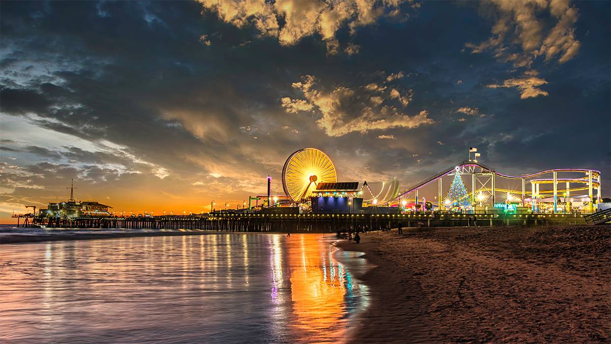 Wide view of Santa Monica Pier at sunset with the Ferris wheel in the center near Los Angeles, California, USA