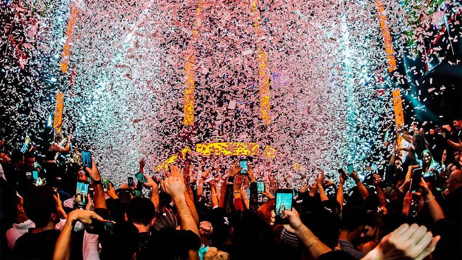 room full of people dancing with bright blue and orange lights and confetti falling down at LIV Nightclub in Miami, Florida, USA