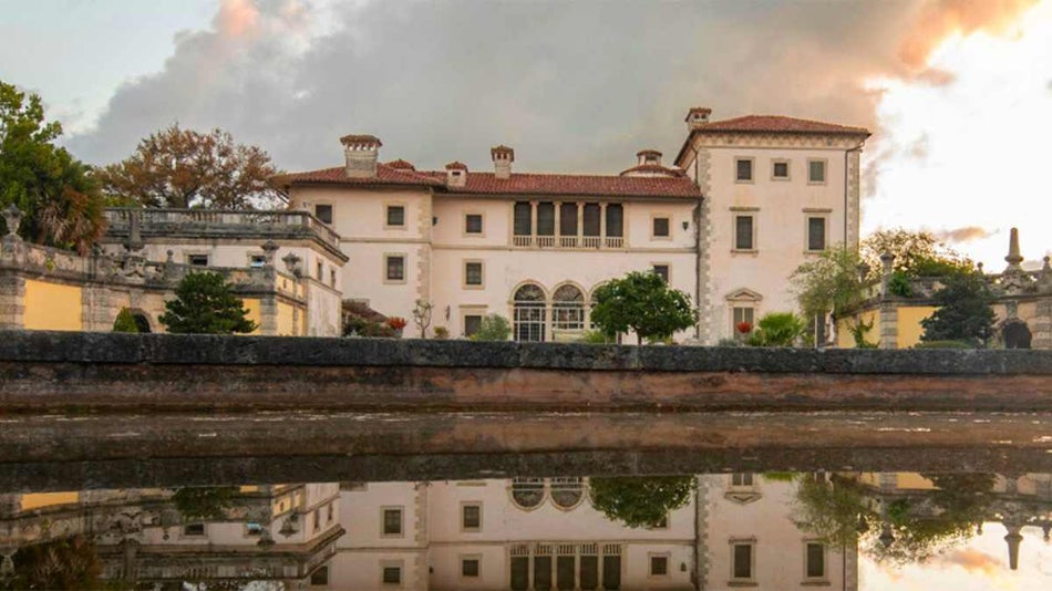 View of Vizcaya Gardens with the buildings reflection in the water at sunset and small trees in front of it in Miami, Florida, USA