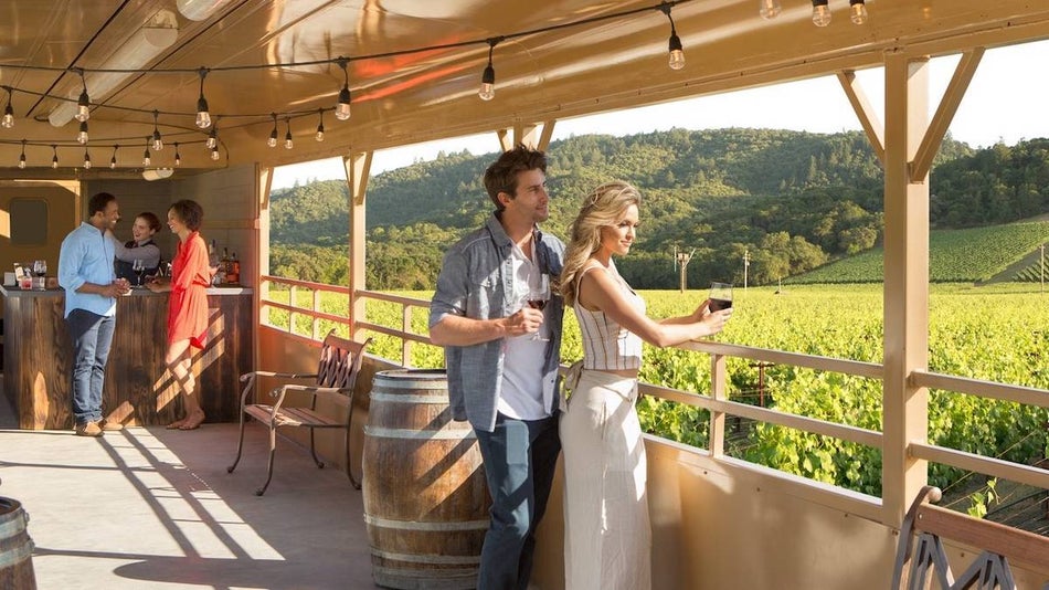 two sets of couples enjoying the scenery and wine aboard the napa valley wine train as they move past green patures and green rolling hills