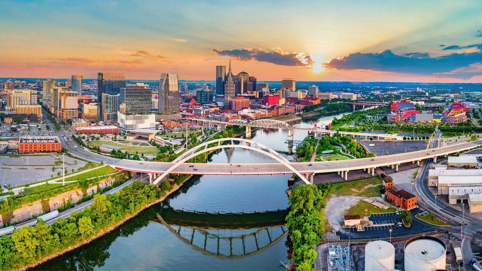 aerial drone view of the Cumberland River and downtown with sun setting in Nashville, Tennessee, USA