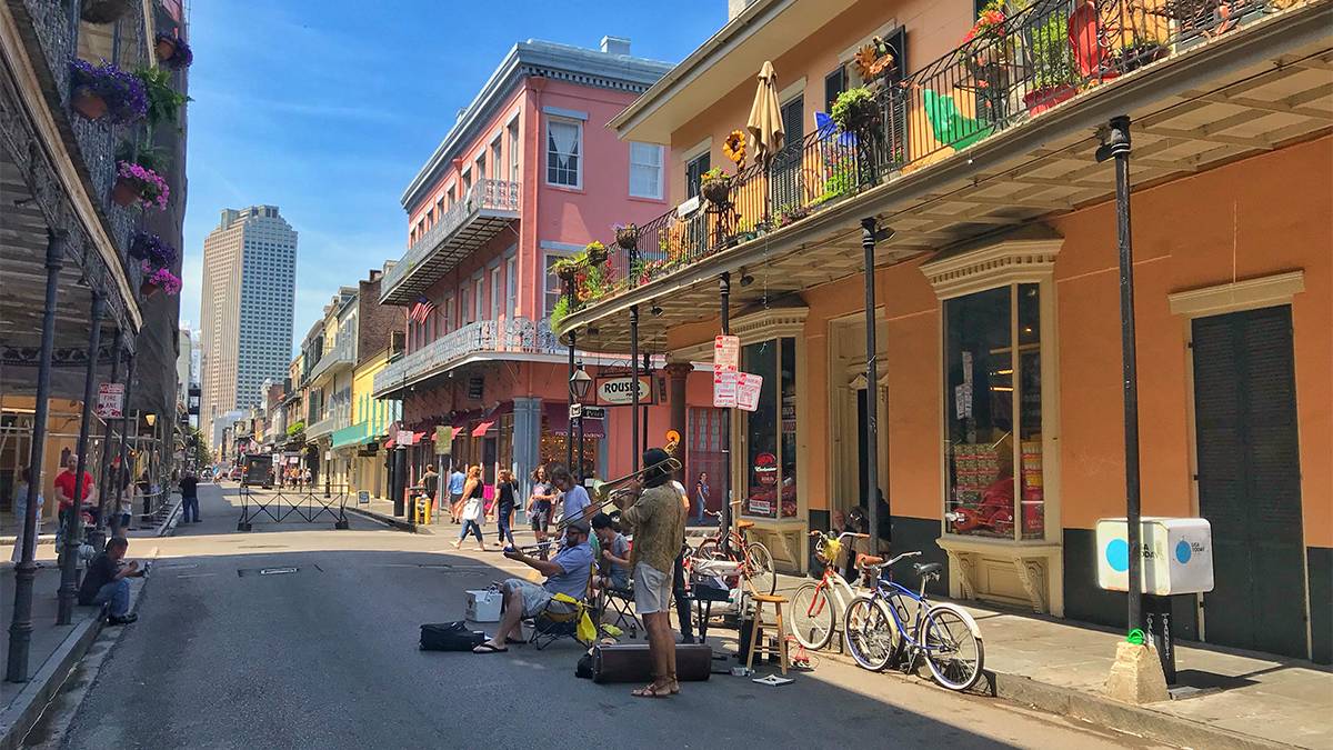 Several musicians playing jazz music on the street in the French Quarter with color full buildings on either side of them and people walking by in New Orleans, Louisiana