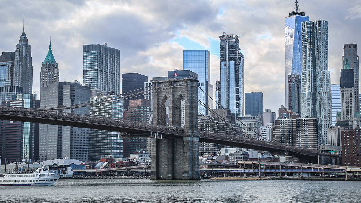 ground view of river and Brooklyn Bridge with skyline in background in NYC, New York, USA