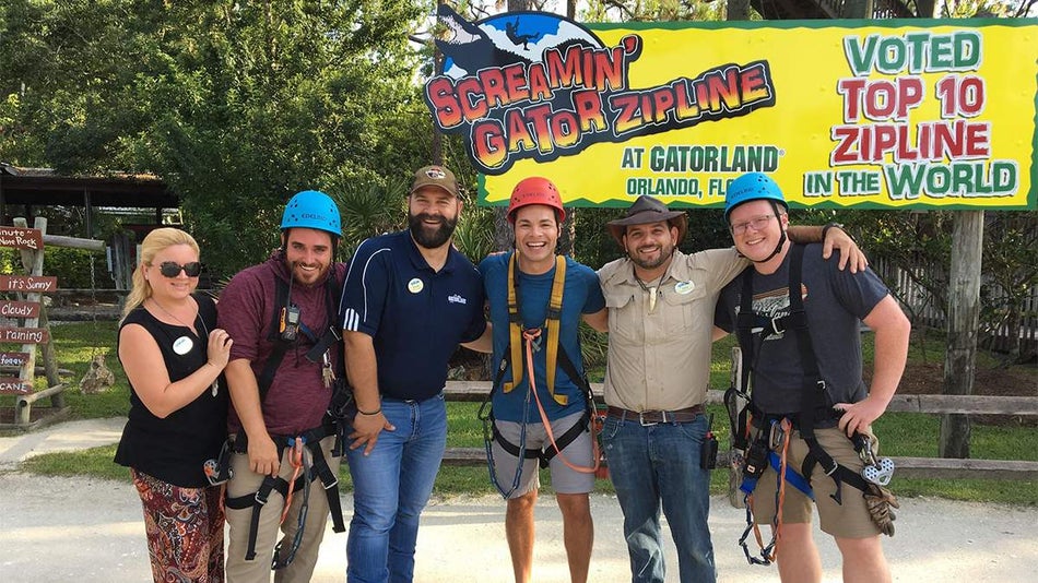 Close up of 5 people posing for a photo, 3 of them in harnesses for zip lining at Gatorland in Orlando, Florida, USA