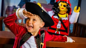 A young boy dressed as a pirate with a LEGO pirate behind him at LEGOLAND Florida in Orlando, Florida, USA