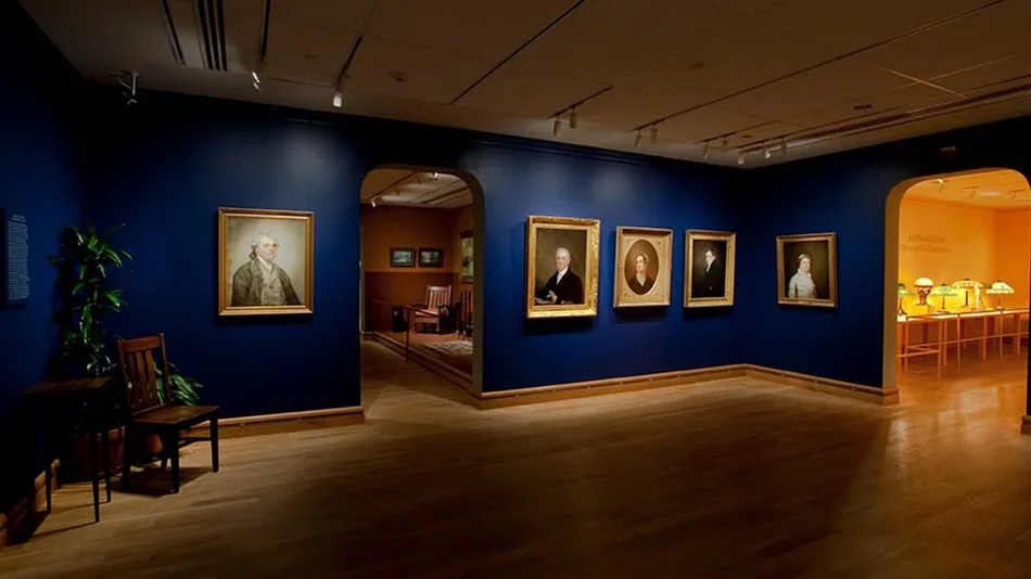 Wide shot of five portraits hung on a dark blue wall with dim lighting at the Morse Museum of Art in Orlando, Florida, USA