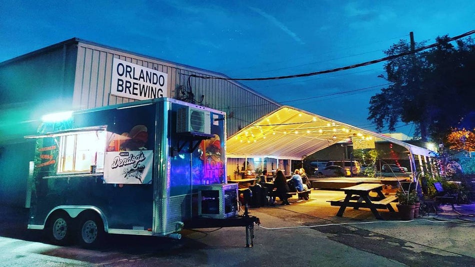 Wide shot of the outdoor lounge area at Orlando Brewing with their warehouse in the background at dusk in Orlando, Florida, USA