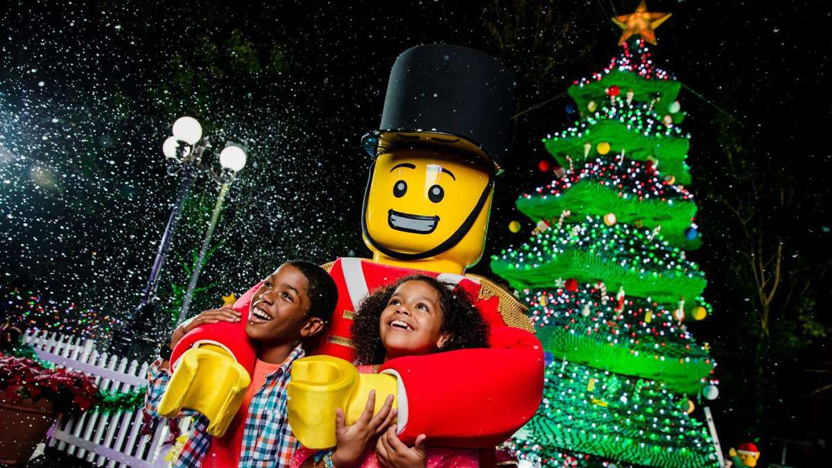 boy and girl posing with LEGOLAND soldier with snow in background and christmas trees in Orlando, Florida, USA