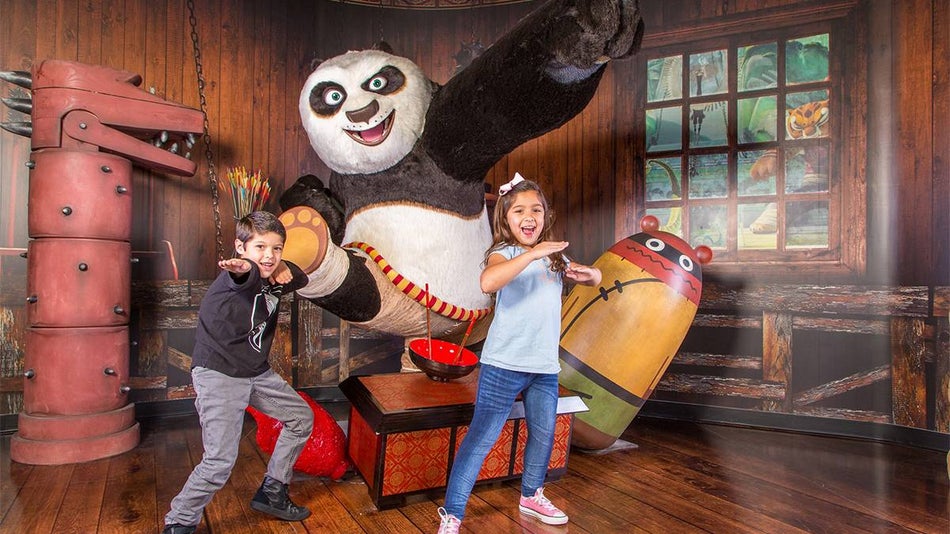 A young boy and girl posing with Po from Kung Fu Panda at Madame Tussauds in Orlando, Florida, USA