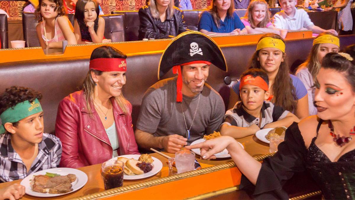 family sitting at dinner with pirate hats being served drinks at Pirates Dinner Adventure in Orlando, Florida, USA