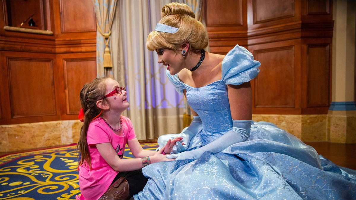cinderella holding hands with a girl in pink shirt and glasses at walt disney world in Orlando, Florida, USA
