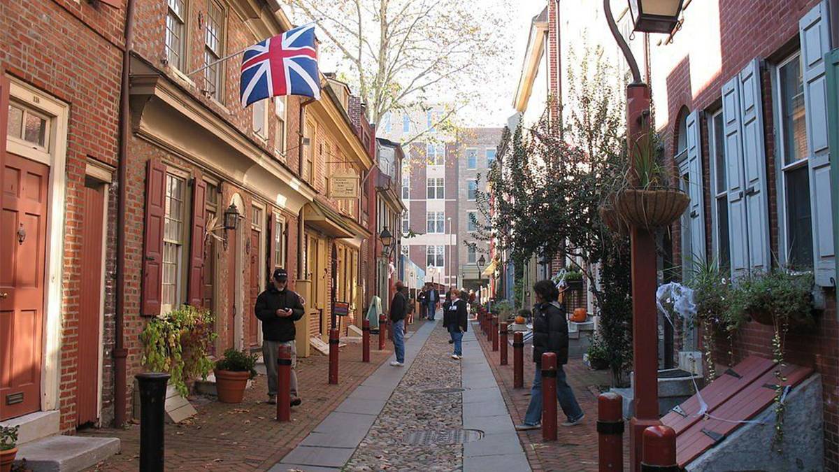 exterior view of historic Elfreth's Alley with people walking past buildings in Philadelphia, Pennsylvania, USA