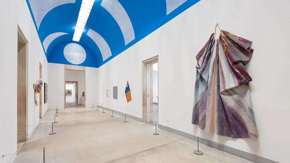 Shot of a hallway with white walls and a blue ceiling with several pieces of abstract art hanging in it at the Philadelphia Museum of Art in Philadelphia, Pennsylvania.