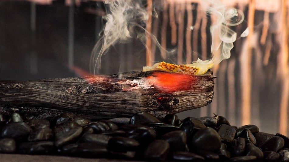 A log red with heat on coals with a piece of sushi on it at Robin in San Francisco, California, USA