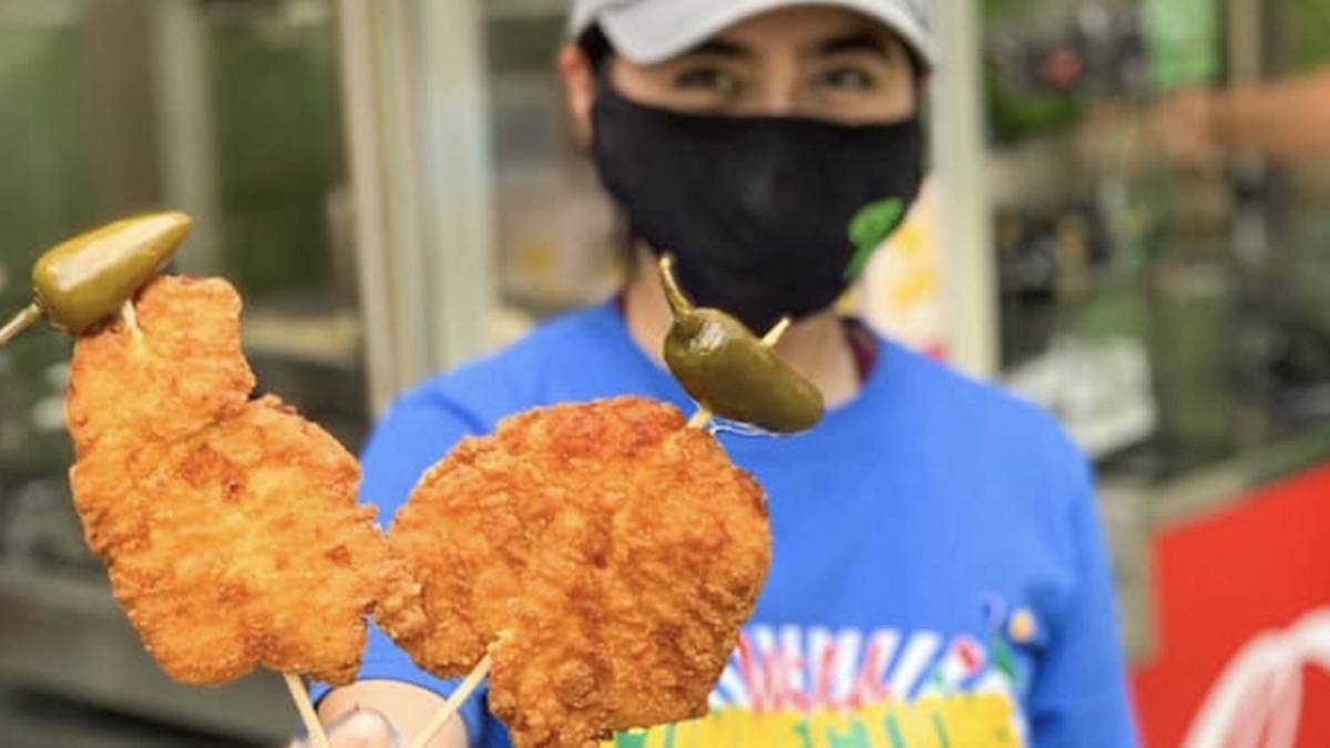 Employee with mask holds up food on skewers at San Antonio Zoo On a Stick festival