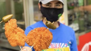 Employee with mask holds up food on skewers at San Antonio Zoo On a Stick festival
