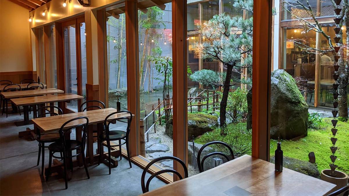 Wooden tables up against a window with a garden on the other side of the windows at Momiji in Seattle, Washington, USA