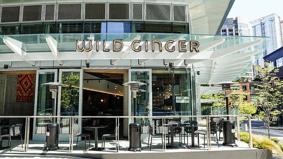 Exterior view of Wild Ginger with its all glass doors and awning plus black metal chairs and tables outside in Seattle, Washington, USA