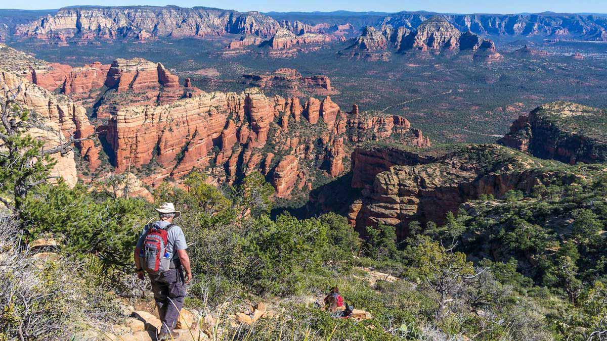 people hiking down trail with red rocks view in the Coconino National Forest near Sedona, Arizona, USA