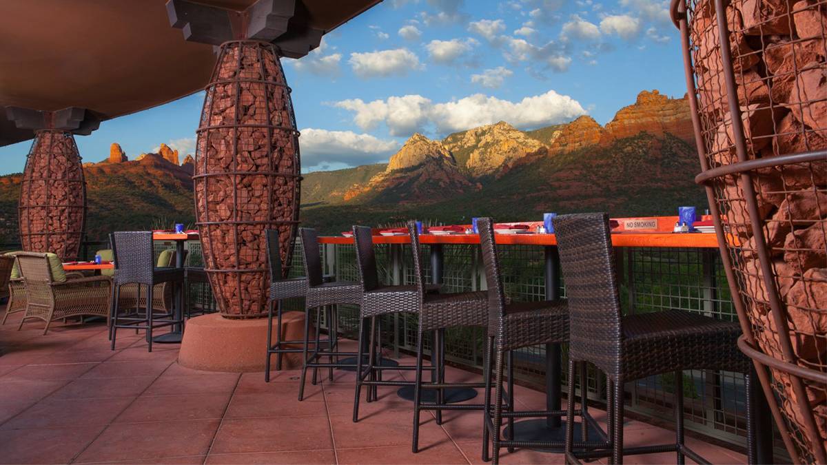 Close up photo of an orange bar with black seats and the beautiful rocky Sedona landscape in the background with a blue sky at Sound Bites Grill in Sedona, Arizona, USA