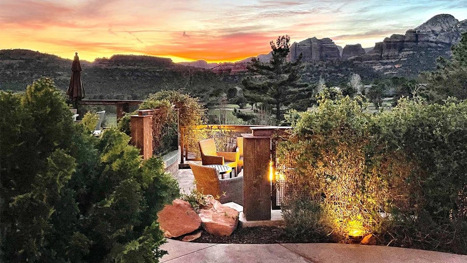 Out door dining area with wicker seats and lots of greenery at sunset with the rocky Sedona landscape behind it at The Spot at Seven Canyons in Sedona, Arizona, USA