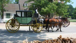 horses pulling green carriage through streets of colonial Williamsburg, Virginia, USA