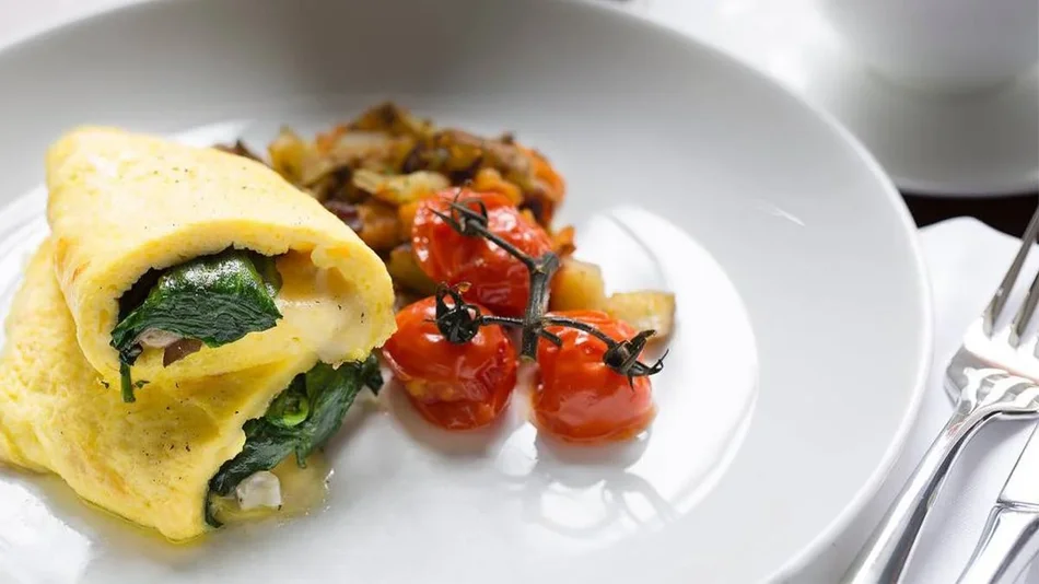 Close up photo of a spinach and cheese omelette with roasted tomatoes and potatoes on the side fromThe Terrace Room at The Williamsburg Inn in Williamsburg, Virginia, USA