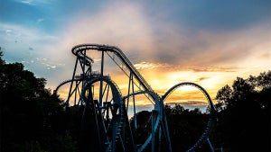 Wide shot of a roller coaster at Busch Gardens with the sun setting behind it in Williamsburg, Virginia, USA
