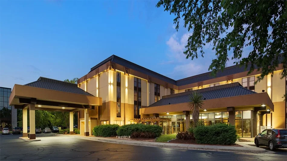 lit up exterior of Best Western Historic Area Inn with car entering drive way and plants near entrance in Williamsburg, Virginia, USA