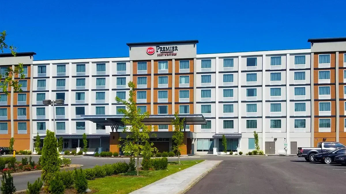 exterior of Best Western Premier Airport Expo Center Hotel during day with cars parked on the side in parking area in Louisville, Kentucky, USA