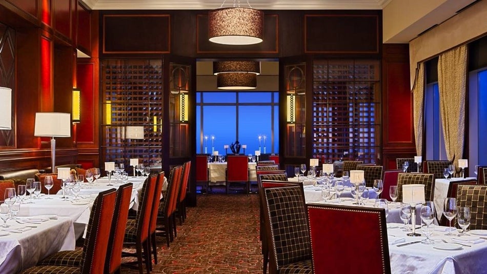 Dimmly lit dining room withrod velvet dining chairs and white clothed tables
