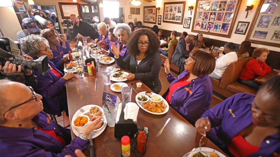Oprah Winfrey sitting at table with guests at the Busy Bee Cafe in Atlanta, Georgia, USA