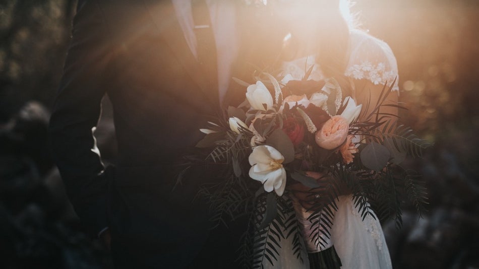 Dimly lit silhouette of bride and groom with a bouquet