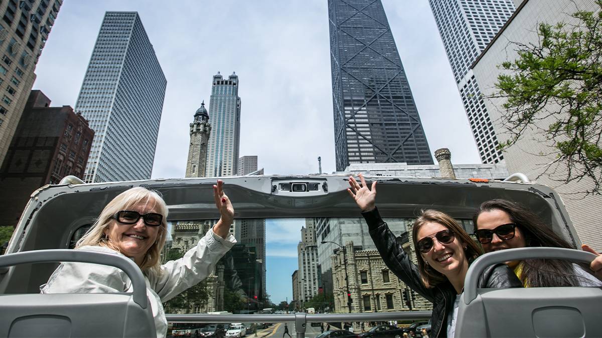 women at the top of the bus with the Sears Tower in background on a Big Bus Tour in Chicago, Illinois, USA