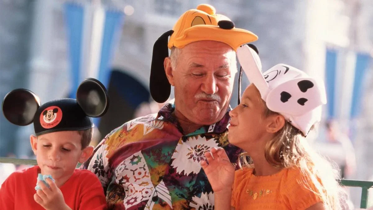 Grandpa with two grandchildren in Disney hats at Walt Disney World in Orlando, Florida, USA