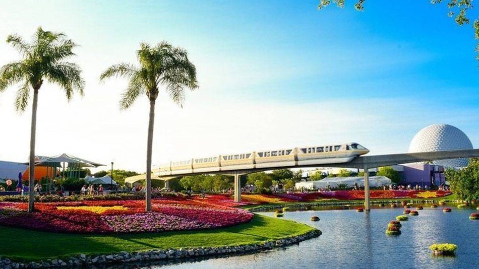 palm tree and spring flowers with Epcot and Walt Disney World Monorail System tram in the background in Orlando, Florida, USA