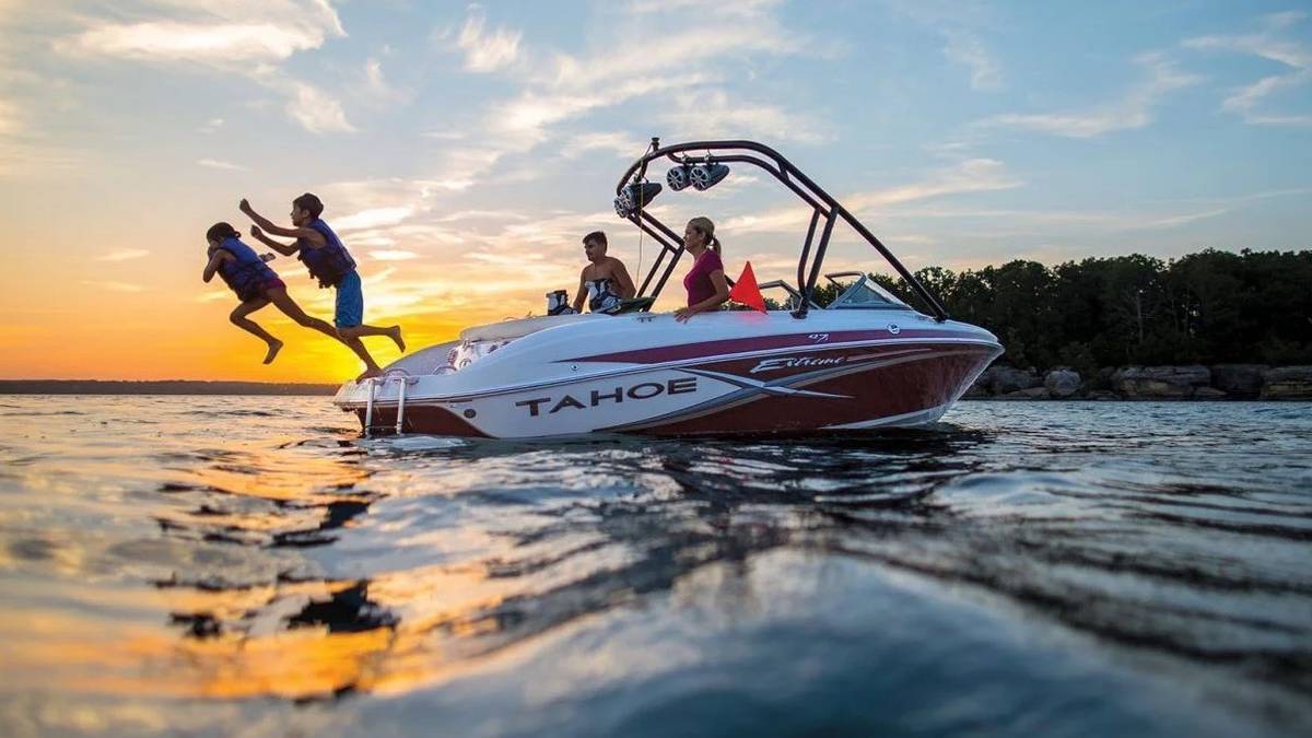 kids jumping from boat into the lake at sunset