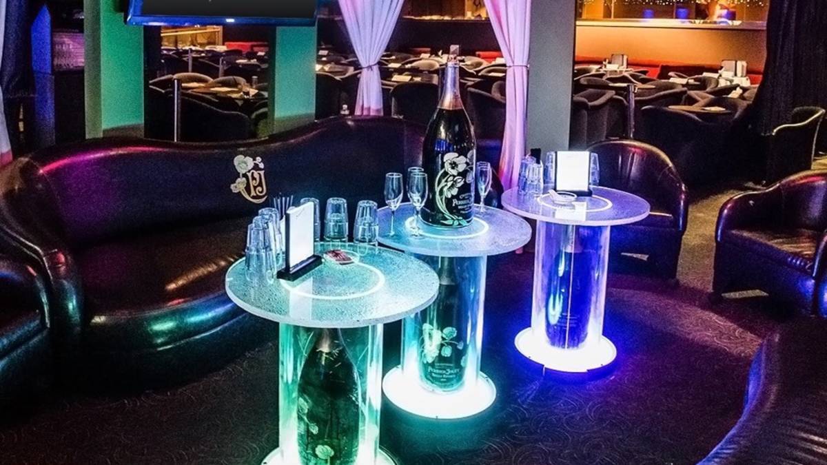 Leather couch with three glass lit tables with champagne glasses and bottles at Sapphire Club in Las Vegas