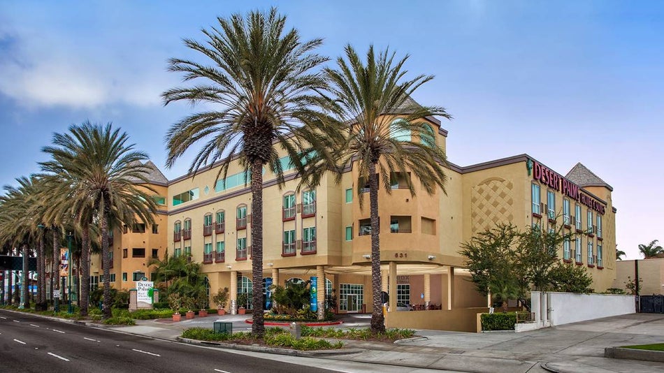 Corner view of the Desert Palms Hotel & Suites landscaped with palm trees and bushes in Los Angeles, California, USA
