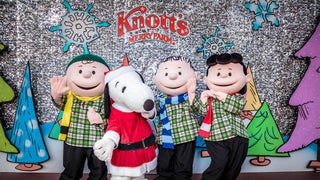 The peanuts in their Christmas outfits and snoopy dressed as Santa standing in front of the Knott's Merry Farm backdrop in Los Angeles, California, USA