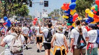 close up of people walking through the streets with colorful balloons and confetti at LA Pride Week Festival in Los Angeles, California, USA