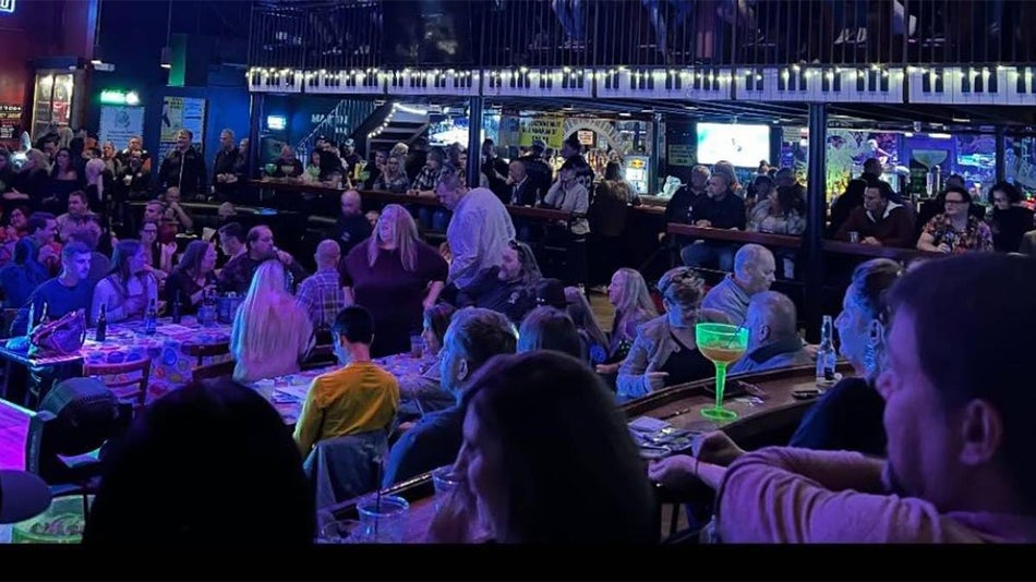 Wide shot of the interior of Crocodile Rocks, a room full of people drinking and piano keys above the bar in Myrtle Beach, South Carolina, USA